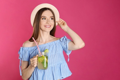 Photo of Beautiful young woman with Mason jar of natural detox lemonade on pink background. Space for text