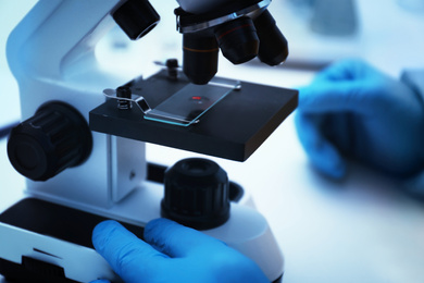 Photo of Scientist using microscope at laboratory, closeup. Virus research