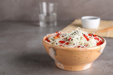 Photo of Bowl of noodles with vegetables on table. Space for text
