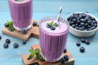 Photo of Tasty blueberry smoothie with mint and fresh berries on light blue wooden table