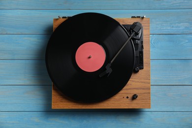 Photo of Modern vinyl record player with disc on blue wooden background, top view