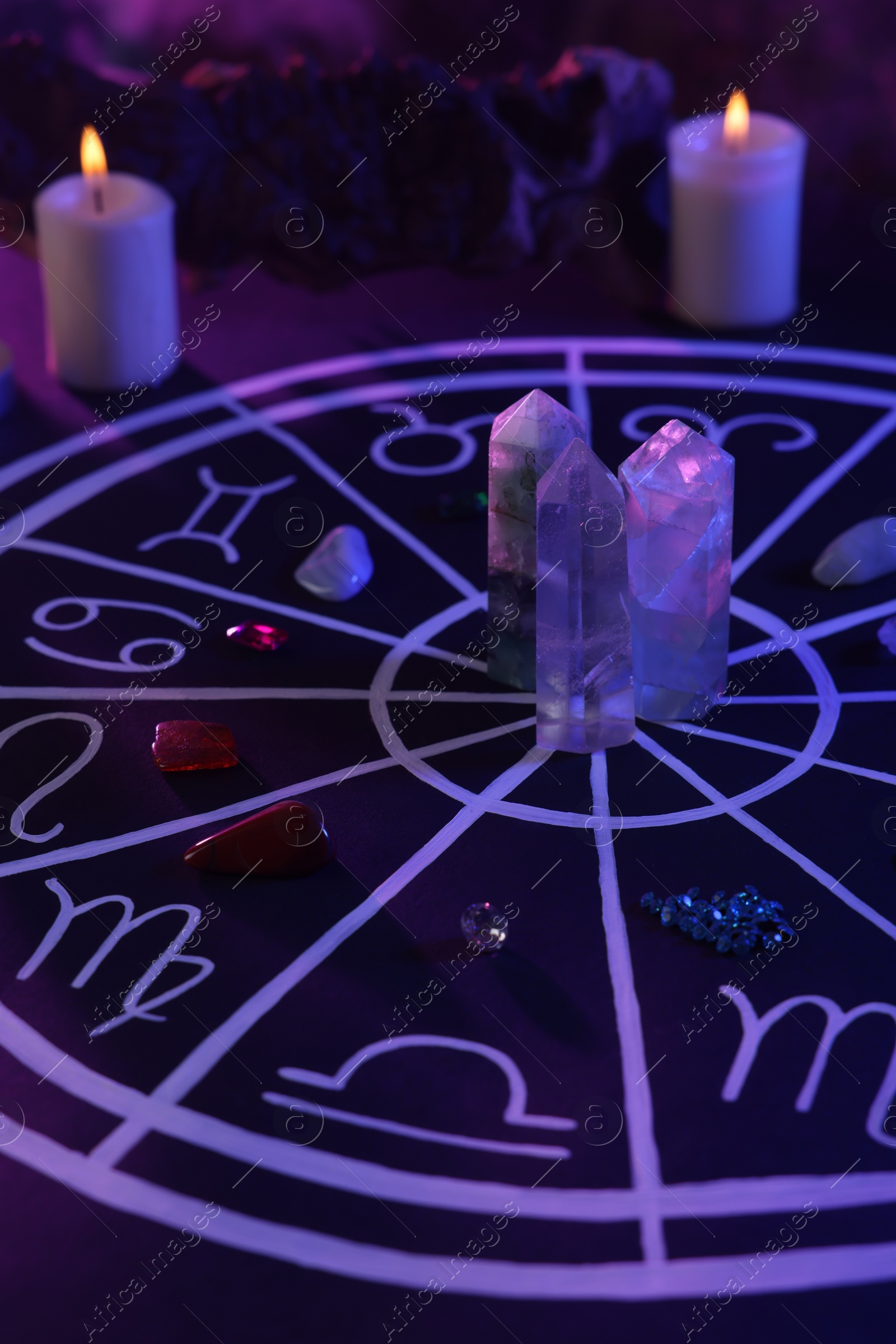 Photo of Natural stones for zodiac signs, drawn astrology chart and burning candles on black table. Color tone effect