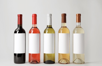 Photo of Bottles of delicious wines with blank labels on white background