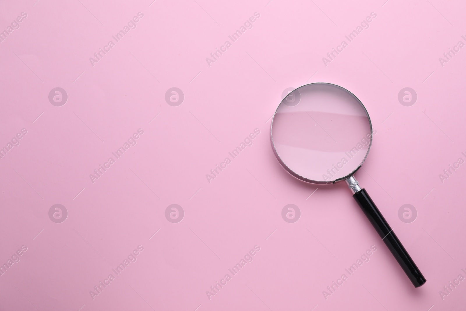 Photo of Magnifying glass on pink background, top view. Space for text