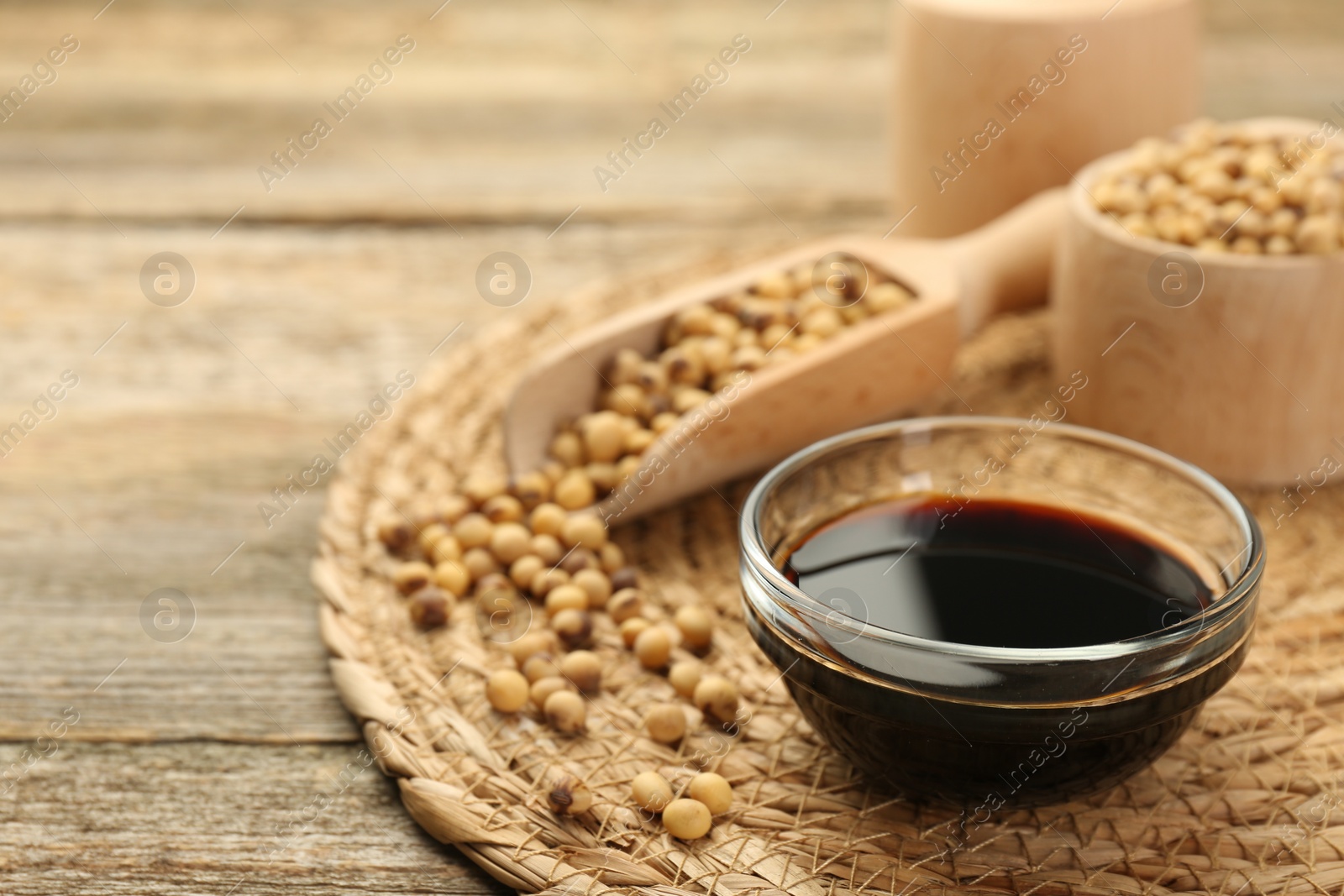 Photo of Soy sauce in bowl and beans on wooden table. Space for text