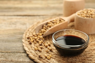 Photo of Soy sauce in bowl and beans on wooden table. Space for text