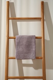 Violet towel hanging on wooden ladder indoors