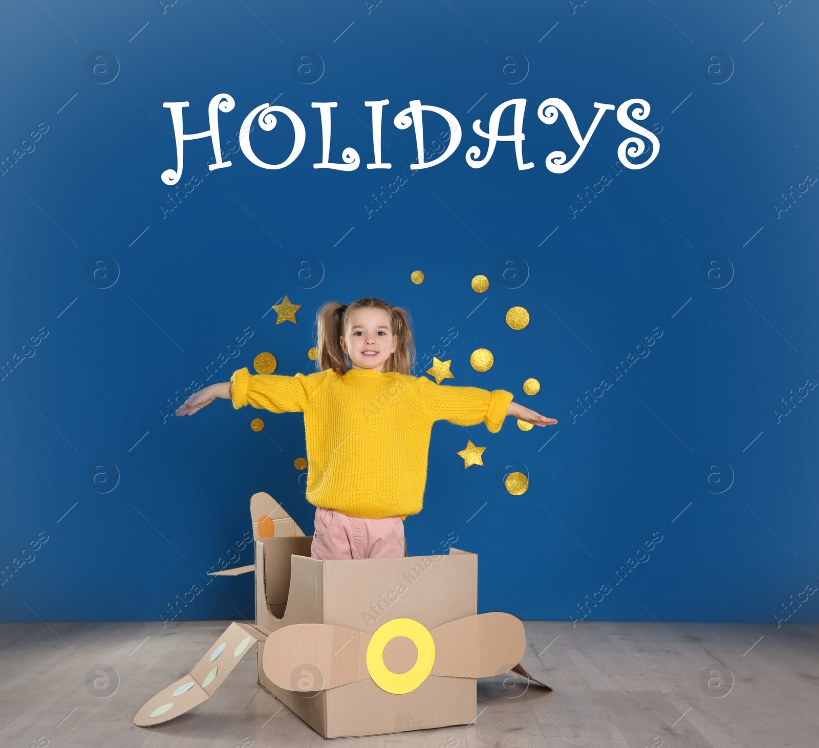 Image of School holidays. Cute little child playing with cardboard plane near blue wall