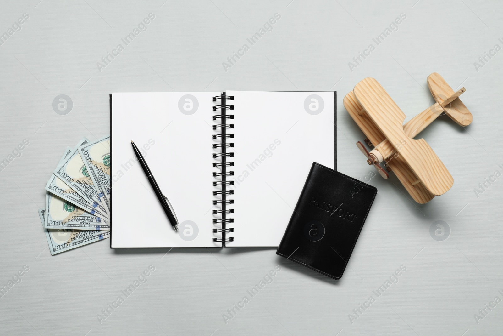 Photo of Flat lay composition with passport, notebook and dollars on light grey table. Business trip