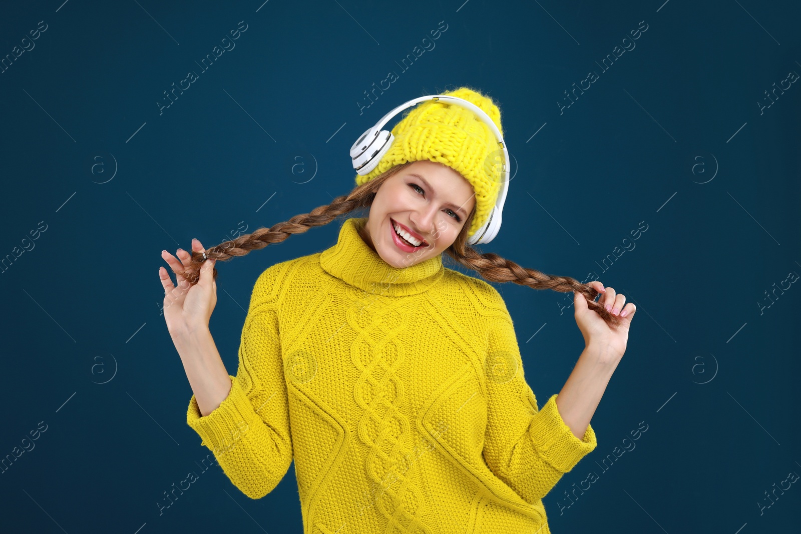 Photo of Young woman listening to music with headphones on dark blue background