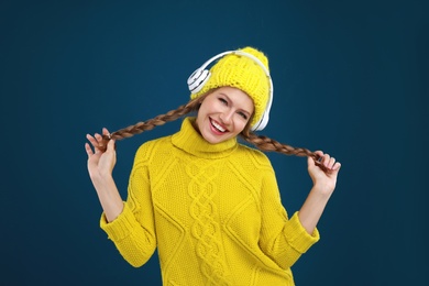 Young woman listening to music with headphones on dark blue background