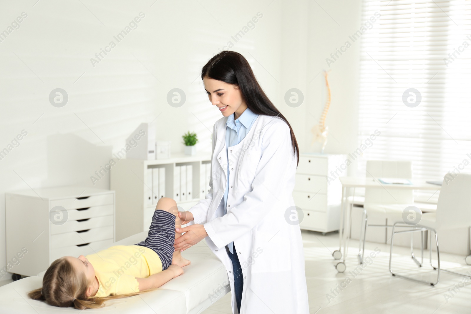 Photo of Professional orthopedist examining little patient's leg in clinic