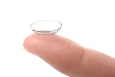 woman holding contact lens on light background, closeup