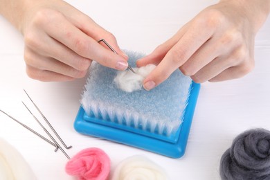 Photo of Woman felting from wool at white wooden table, closeup