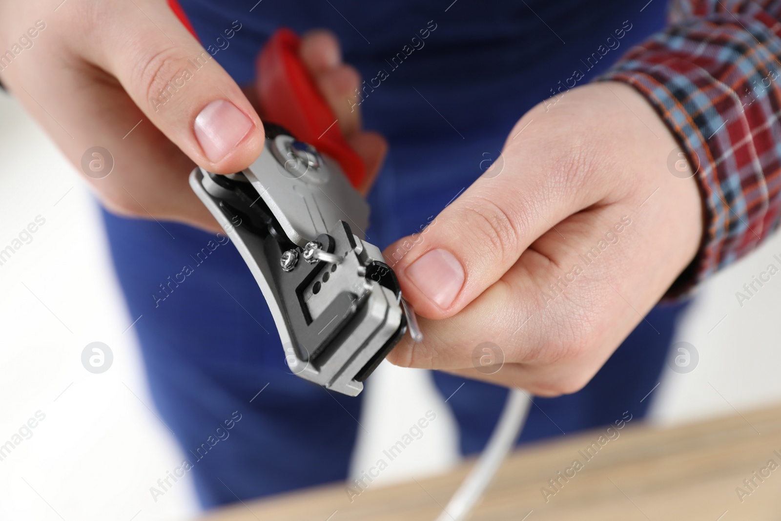 Photo of Professional electrician stripping wiring on white background, closeup