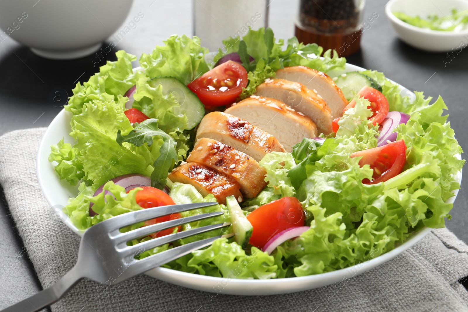 Photo of Eating delicious salad with chicken and vegetables at table, closeup