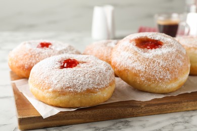 Photo of Delicious donuts with jam and powdered sugar on white marble table, closeup