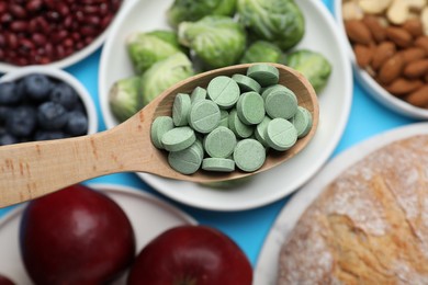 Photo of Holding spoon with prebiotic pills over food, top view