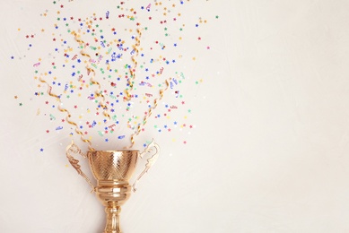 Photo of Trophy and confetti on light background, top view with space for text. Victory concept