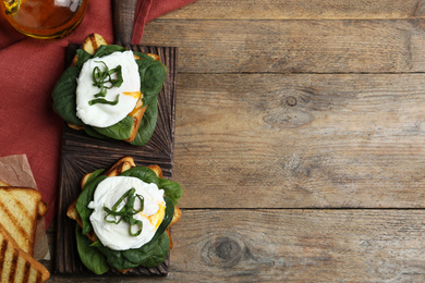 Photo of Delicious poached egg sandwiches served on wooden table, flat lay. Space for text