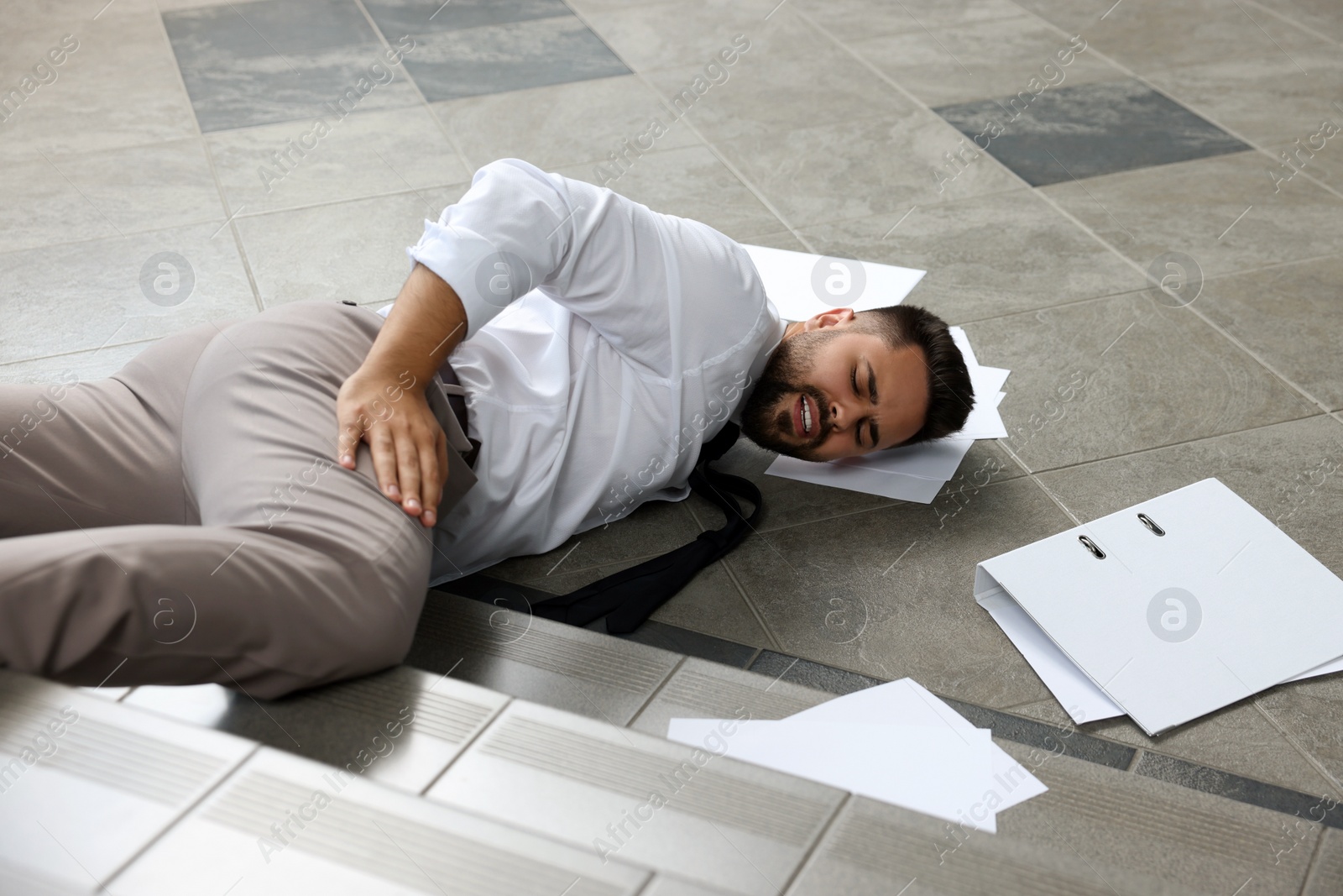 Photo of Man fallen down stairs suffering from pain indoors