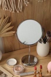 Mirror and makeup products on wooden dressing table