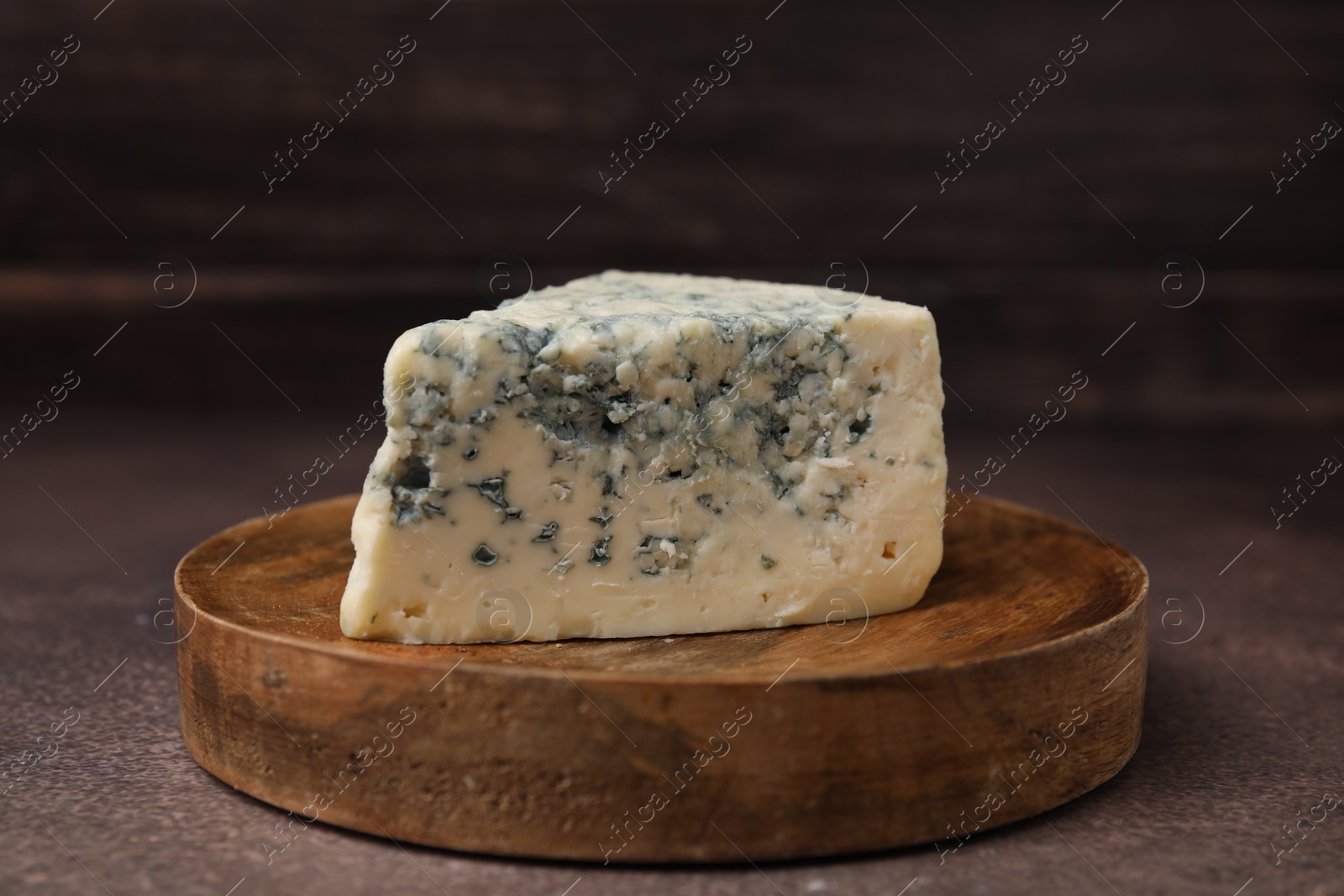 Photo of Piece of tasty blue cheese on brown table