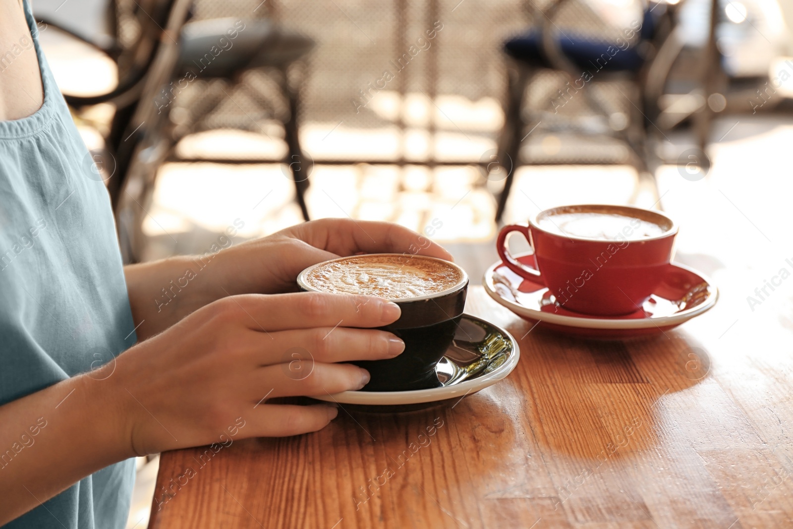 Photo of Woman with cup of fresh aromatic coffee at table, closeup