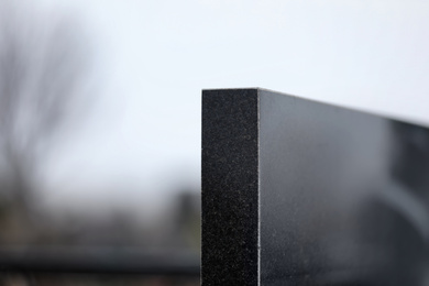 Black granite tombstone outdoors, closeup with space for text. Funeral ceremony