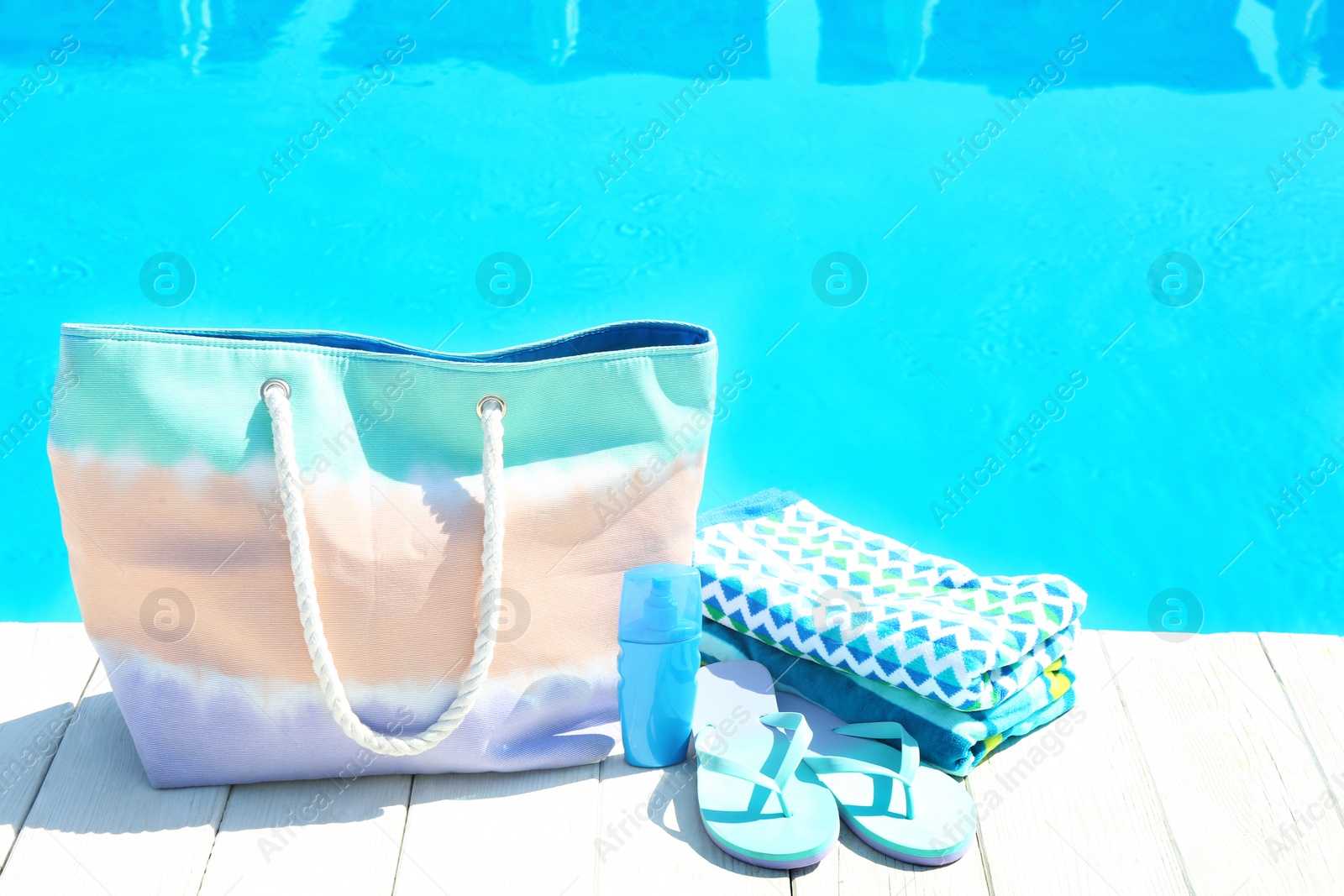 Photo of Beach accessories on wooden deck near swimming pool. Space for text