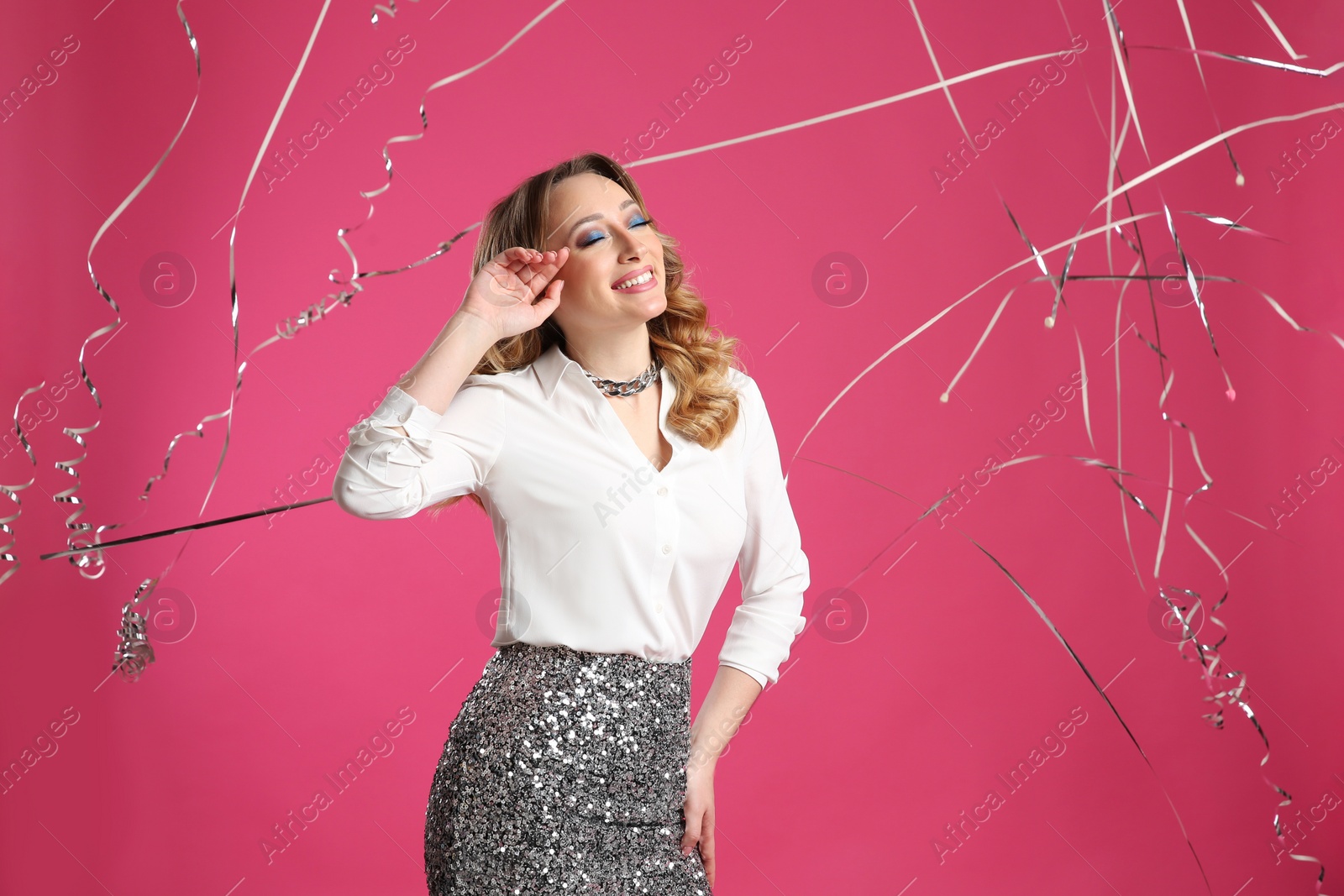 Photo of Happy woman and falling down serpentines on pink background