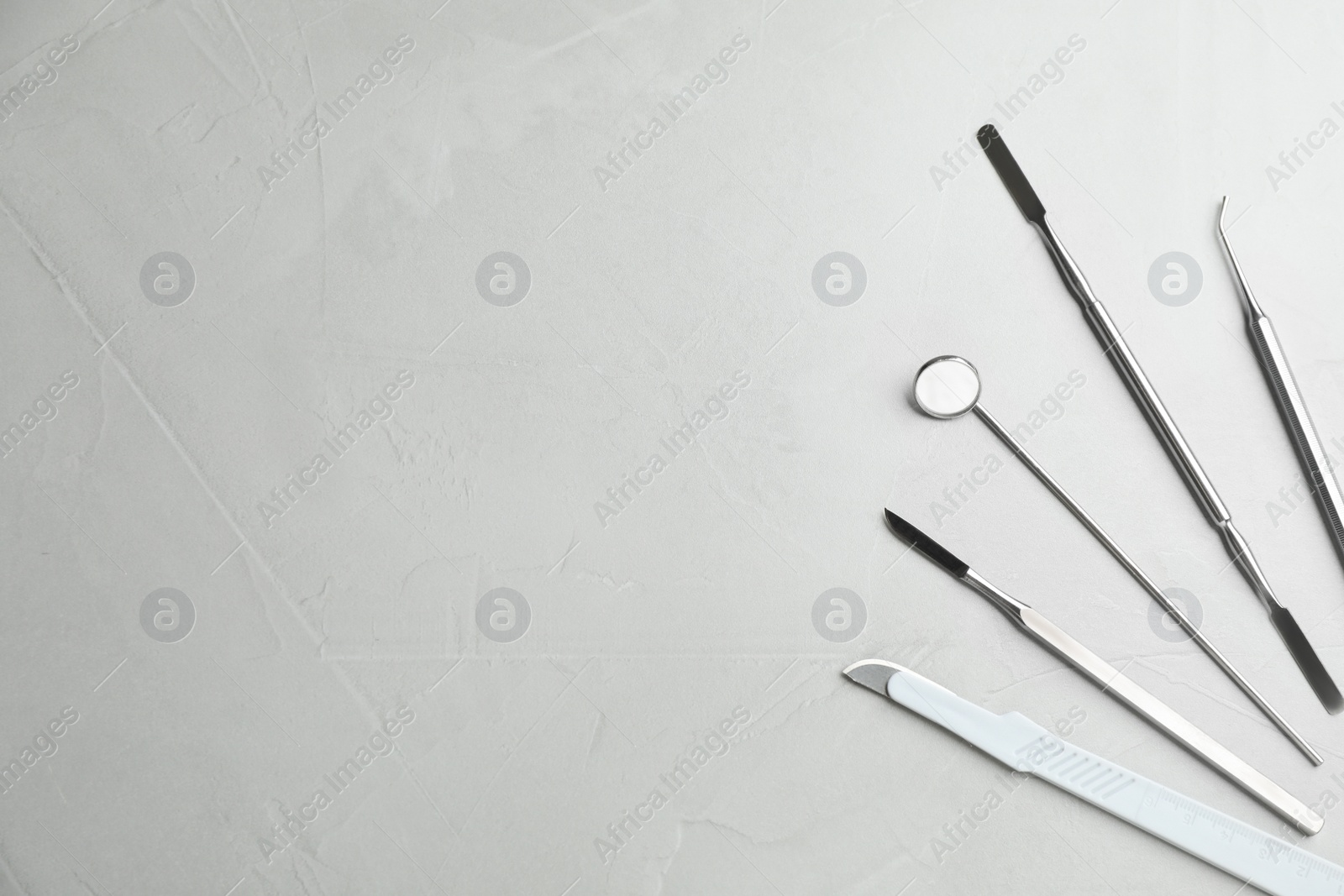 Photo of Set of different dentist's tools on light grey table, flat lay. Space for text