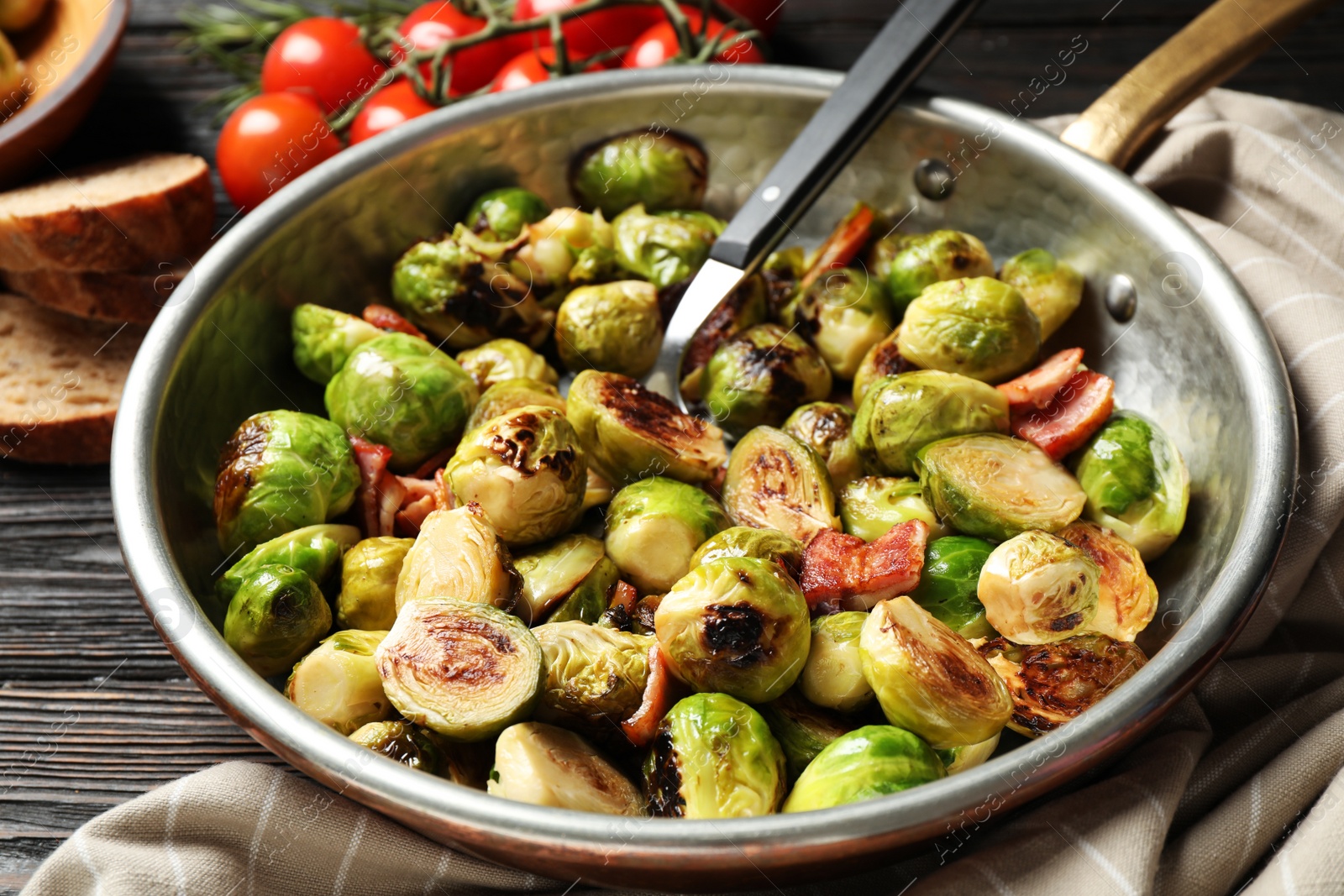 Photo of Delicious Brussels sprouts with bacon in pan on table