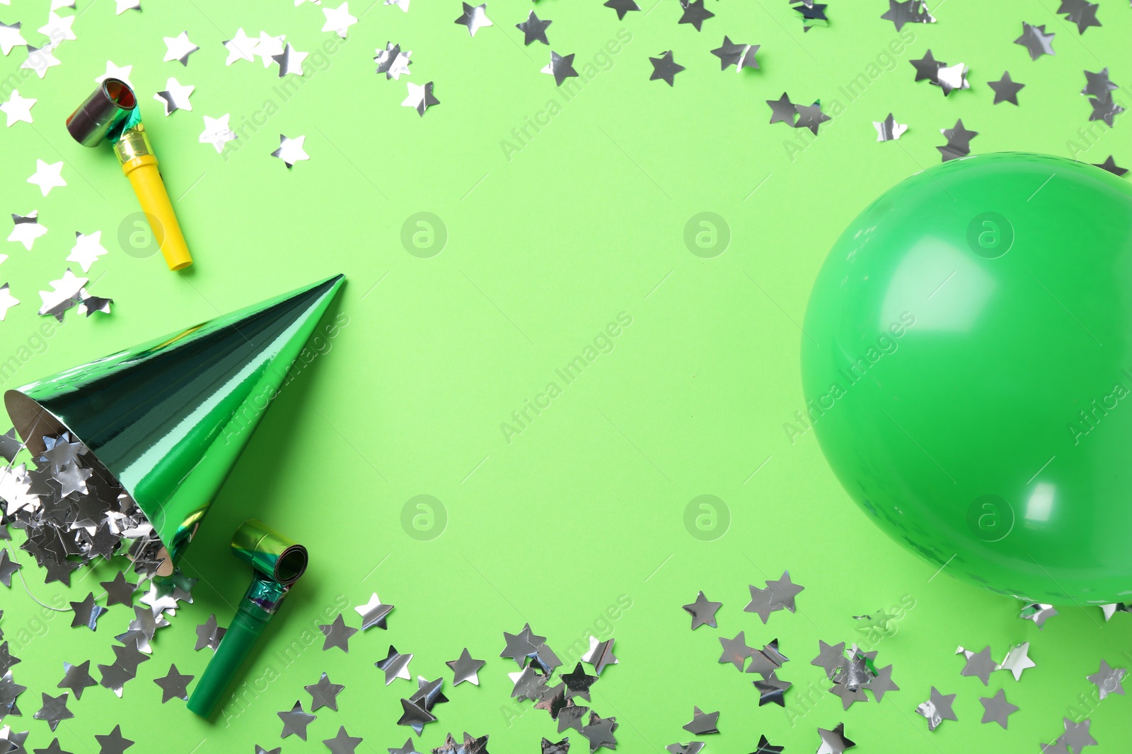 Photo of Frame made of party hat and other bright decor on light green background, flat lay. Space for text