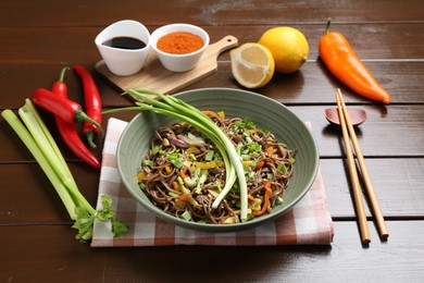 Photo of Stir-fry. Delicious cooked noodles with chicken and vegetables in bowl on wooden table