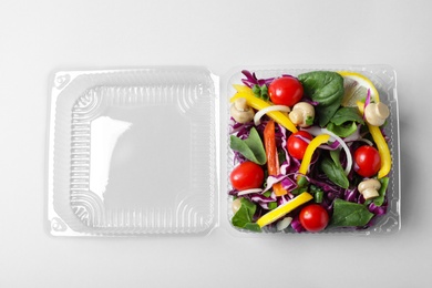 Photo of Plastic container with fresh salad on white background, top view