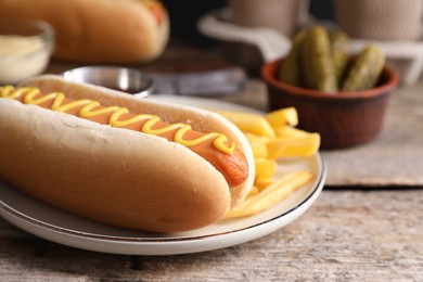 Delicious hot dog with mustard and French fries on wooden table, closeup