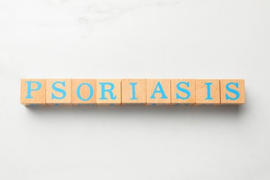 Word Psoriasis made of wooden cubes with letters on white table, top view