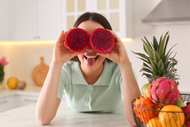 Photo of Young woman with fresh pitahaya in kitchen. Exotic fruit