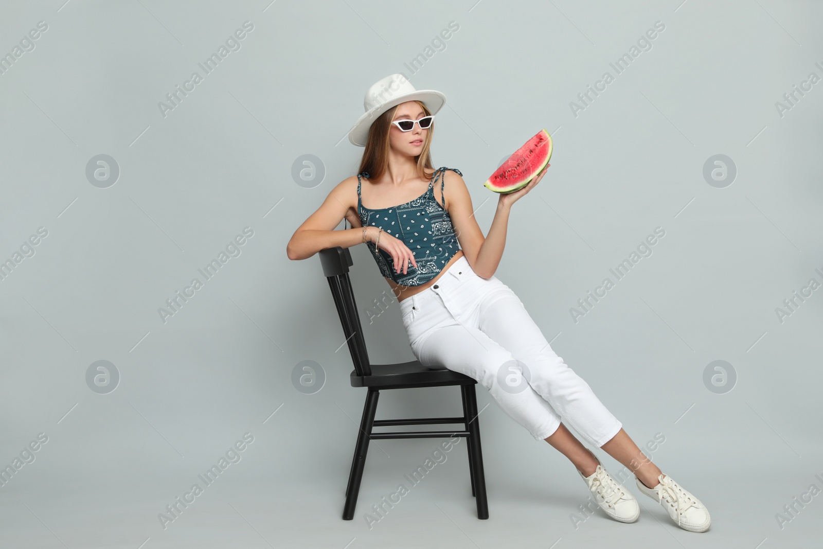 Photo of Beautiful girl on chair with watermelon against grey background