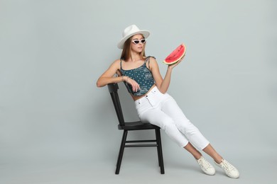 Photo of Beautiful girl on chair with watermelon against grey background