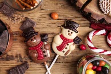 Flat lay composition with funny chocolate snowmen candies on wooden table