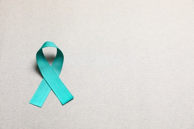Photo of Teal awareness ribbon on grey paper, above view with space for text. Symbol of social and medical issues
