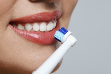 Photo of Woman brushing her teeth with electric toothbrush on white background, closeup. Space for text