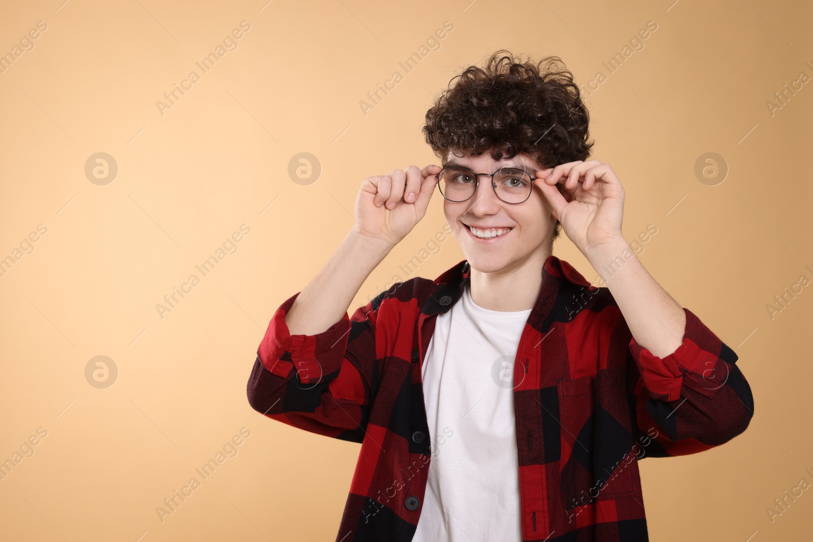 Photo of Portrait of happy teenage boy wearing glasses on beige background. Space for text