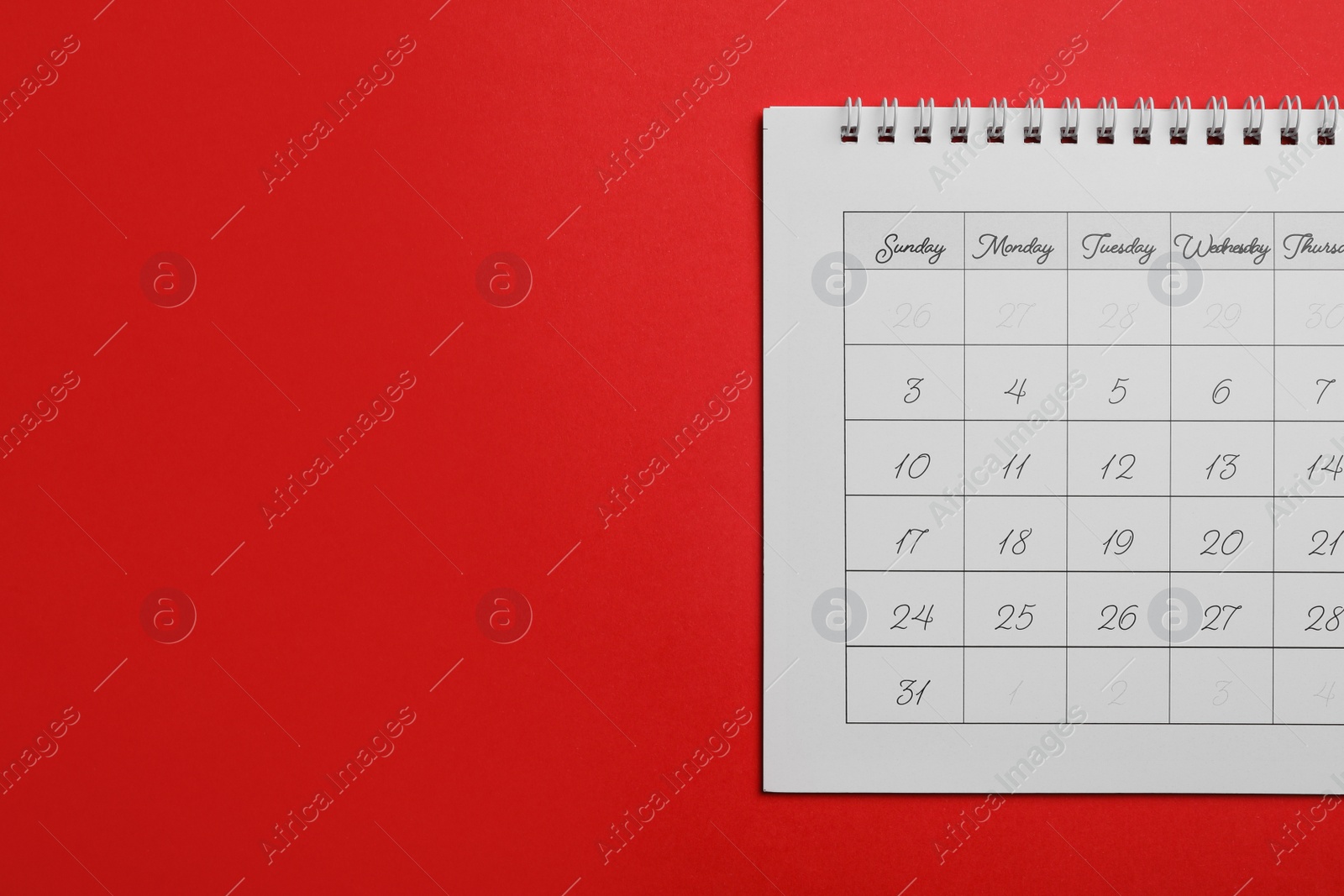 Photo of Paper calendar on red background, top view. Space for text