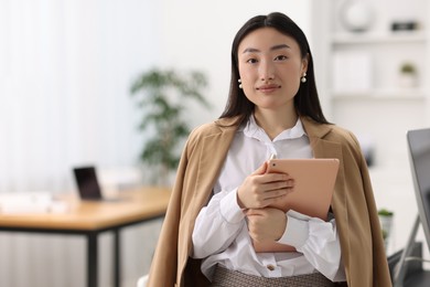 Portrait of beautiful businesswoman with tablet in office. Space for text