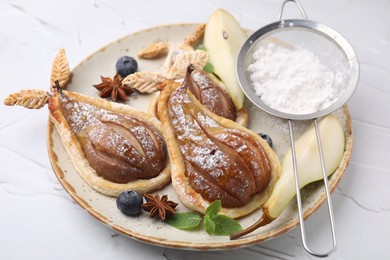Photo of Delicious pears baked in puff pastry with powdered sugar served on white table, closeup