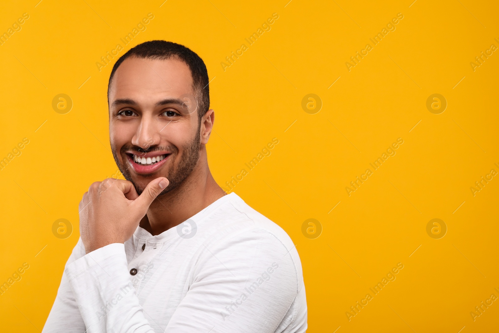 Photo of Portrait of smiling man with healthy clean teeth on orange background. Space for text