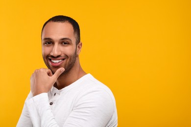 Photo of Portrait of smiling man with healthy clean teeth on orange background. Space for text